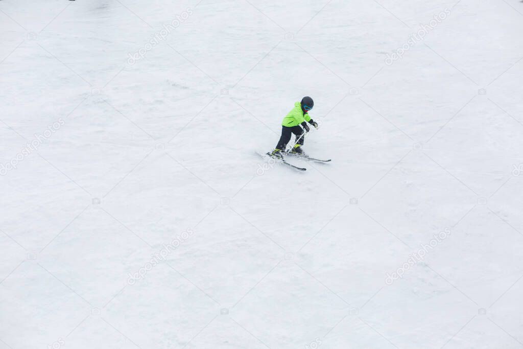 A child skiing alone down the hill at high speed.
