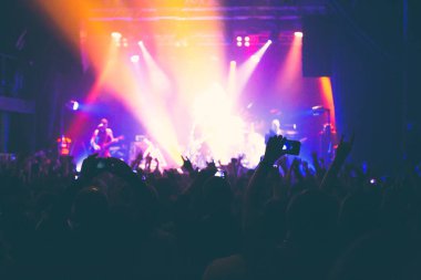 Büyük bir konser kulübünde konserin izleyicileri..