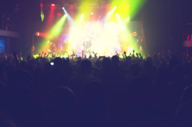 Büyük bir konser kulübünde konserin izleyicileri..