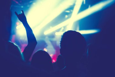 Büyük bir konser kulübünde konserin izleyicileri..