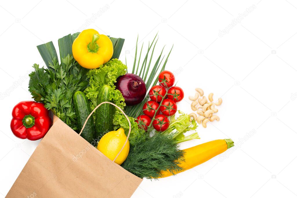 A set of vegetables and herbs in a paper bag isolated on white background. Concept: Shopping in a supermarket or market and Healthy Vegetarian Food.