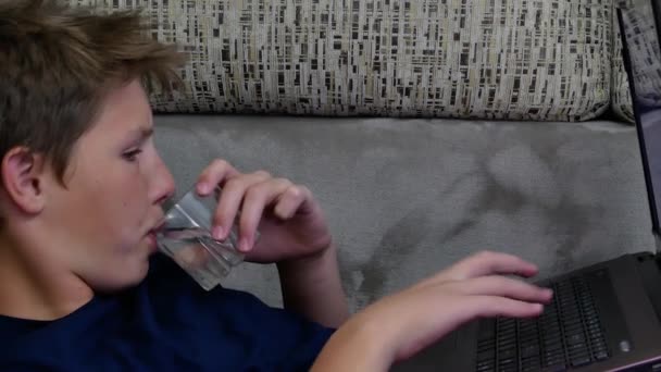 Подросток с ноутбуком и стаканом воды. — стоковое видео