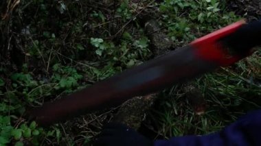 Eldivenli eller testere ile bir kütük kesiyor..