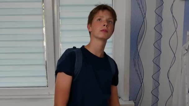 Niño en una habitación con una mochila escolar. — Vídeo de stock