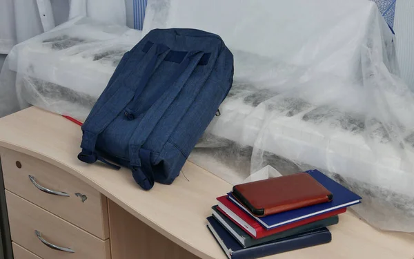 Blue School backpack and textbooks, notebooks on the students desk. Stock Photo