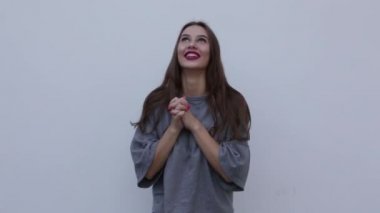 Uzun saçlı, gri gömlekli güzel bir kız gülüyor ve ellerini çırpıyor.. 