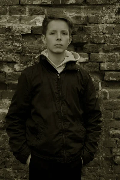 Portrait of a boy standing against a brick wall. — Stock Photo, Image