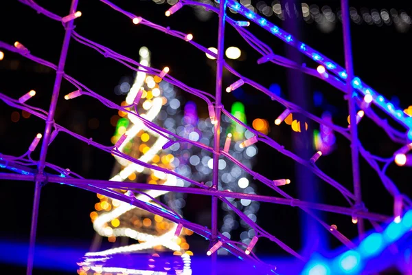 Glowing lights on the backdrop of a further standing artificial Christmas tree with electric lights. — Stock Photo, Image