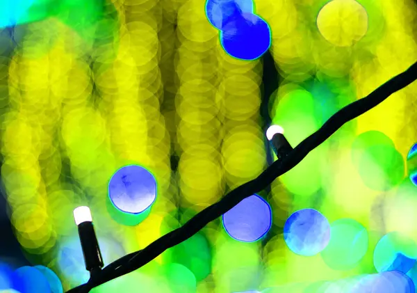 Blue bokeh close-up on a blurry backgroundof yellow garlands. — Stock Photo, Image