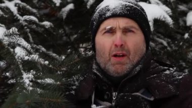 Donmuş bir adam ceketini doğada ilikliyor..