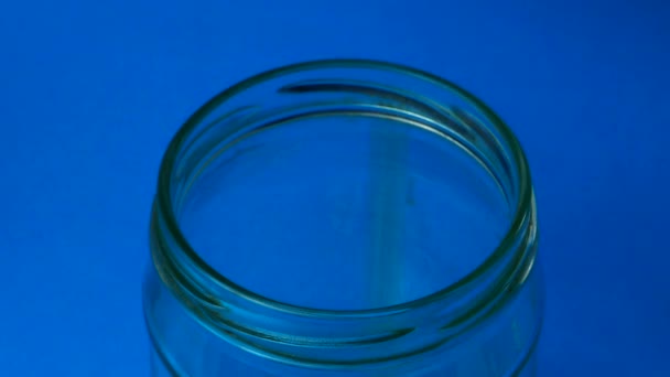 Visolie capsules vallen in een glazen pot. — Stockvideo