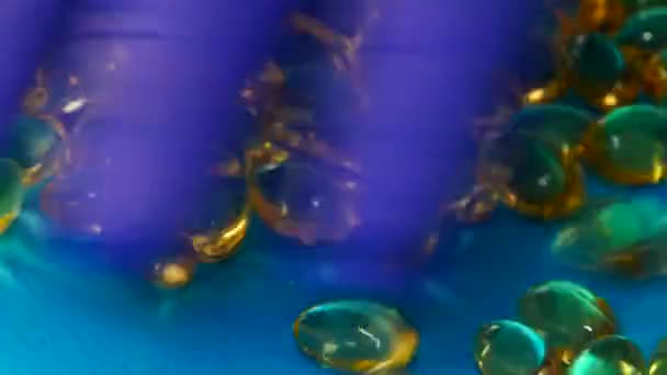 Capsules of fish oil on a blue background are being sorted by hand. — Stock Video