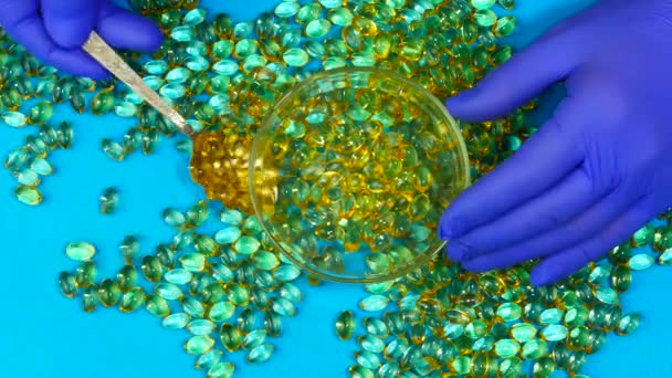 Mãos usando luvas médicas azuis pegar as cápsulas de gelatina com uma colher. — Vídeo de Stock