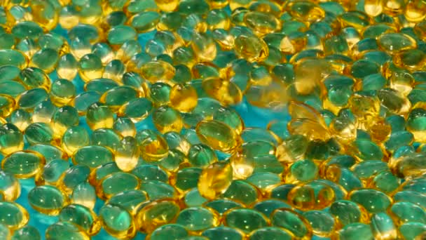 Желтые фармацевтические капсулы катятся на голубом фоне. — стоковое видео