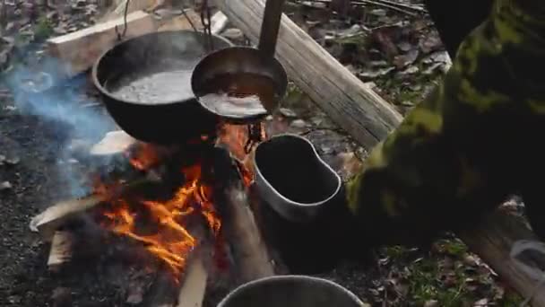 Mãos derramam chá de um grande caldeirão em uma panela pequena. — Vídeo de Stock
