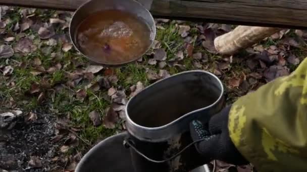 Verter una bebida caliente en una olla en la naturaleza. — Vídeos de Stock