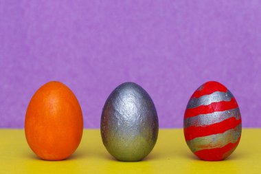 İki tonluk arka planda üç renkli ahşap ev ödevi yumurtası..