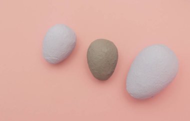 Üç dekoratif yumurta, pembe arka planda elle boyanmış..