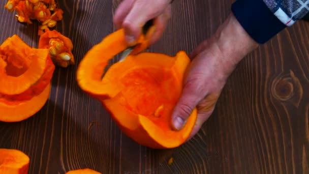 Mãos masculinas cortam abóbora laranja em pequenas fatias. — Vídeo de Stock