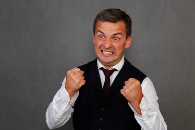 Portrait of a man of 30-35 years old clenching his fists in anger.