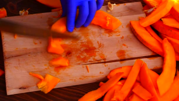 Hands in blue rubber gloves slicing a fresh pumpkin. — Vídeos de Stock