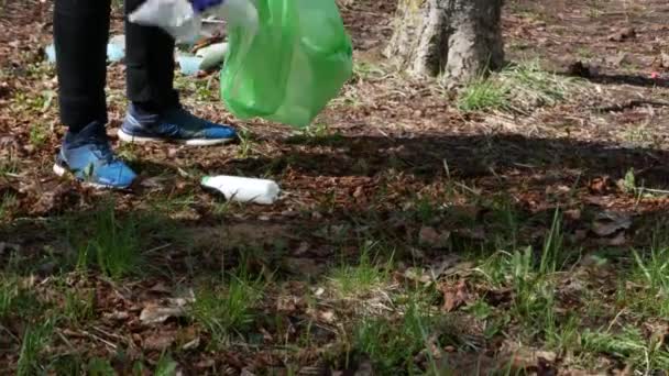 Tonårspojken samlar plastavfall från marken i skogen. — Stockvideo