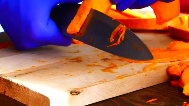 As mãos usando luvas de borracha cortam a abóbora em uma placa. — Vídeo de Stock