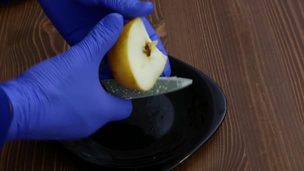 Handschoenen van rubber snijden een stuk appel in tweeën.. — Stockvideo