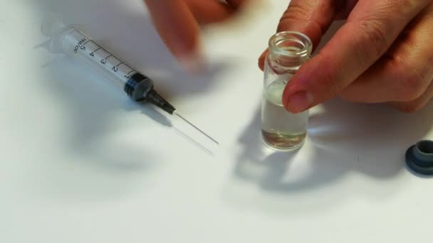 Het witte vaccin in de fles, met de spuit in close-up, tegen een witte achtergrond. — Stockvideo