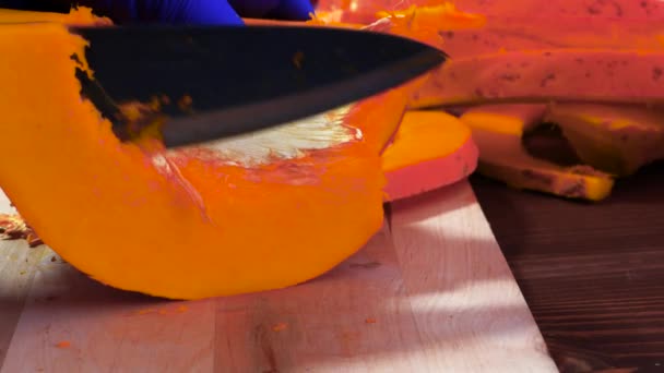 Manos en guantes de goma azul cortando calabaza. — Vídeos de Stock