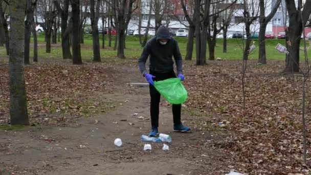 Dobrovolný teenager uklízí odpadky v parku. — Stock video