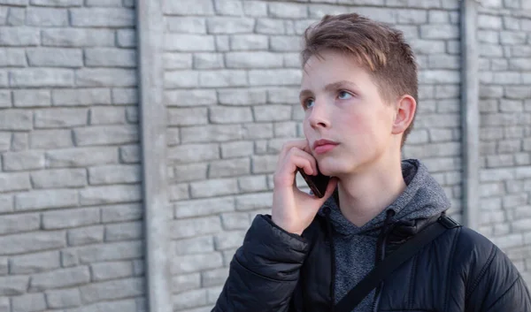 Porträtt av en pojke 15 år med en smartphone i handen. — Stockfoto