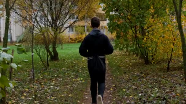 Um adolescente caminha em um parque da cidade. — Vídeo de Stock