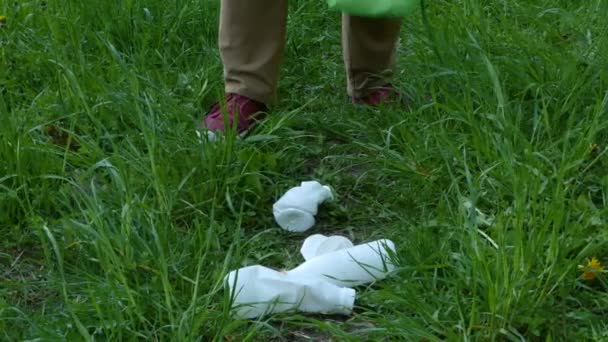 Teenager sbírat plastový odpad na trávě. — Stock video