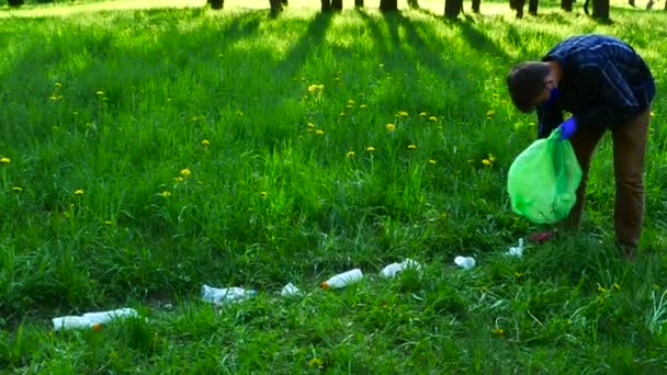 Adolescente en el bosque recogiendo botellas de plástico, basura en el bosque de primavera. — Vídeo de stock