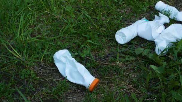 Använda vita plastflaskor ligger på grönt gräs. — Stockvideo