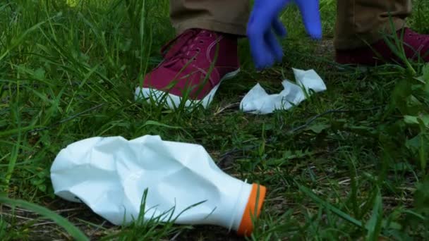 手戴蓝色手套，用塑料袋在草地上收集用过的塑料瓶 — 图库视频影像