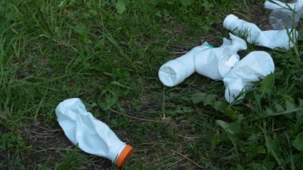 Använda plastflaskor av vit färg i skogen på gräset. — Stockvideo