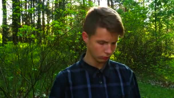En tonåring i parken håller en telefon i sina händer. — Stockvideo