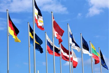 Mavi gökyüzünün arka planında farklı ülkelerin bayrakları