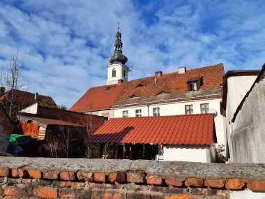 Parlak mavi gökyüzüne karşı, yıpranmış çatıları ve klasik bir kilise kulesi olan büyüleyici Avrupalı eski kasaba cazibesini keşfedin. Seyahat ve mimari temalar için mükemmel.