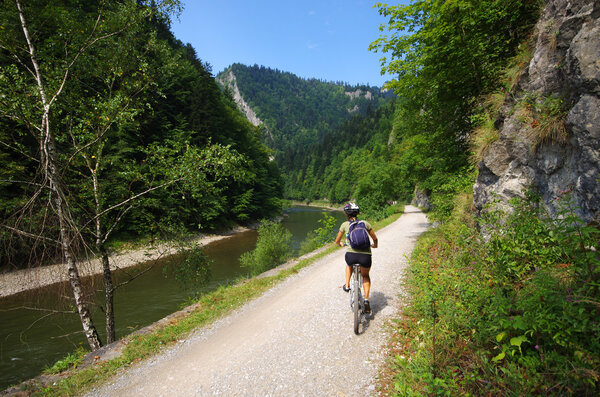 Young woman cycling along Dunajec river, Poland
