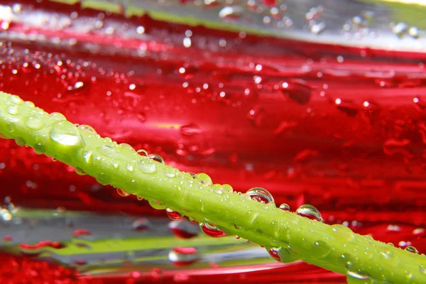 Gotas de agua brillante rociadas sobre la superficie roja texturizada . — Foto de Stock