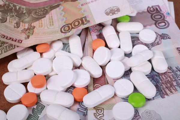 Pillen van verschillende kleuren op geld achtergrond. — Stockfoto