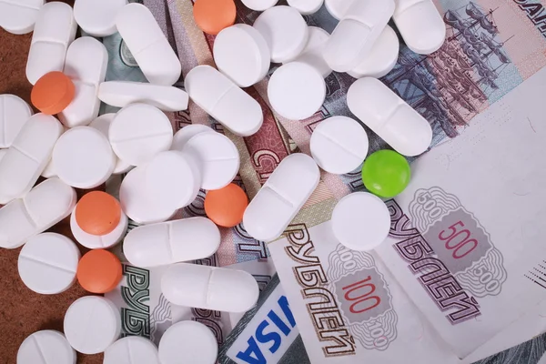 Таблетки різних кольорів на фоні грошей . — стокове фото