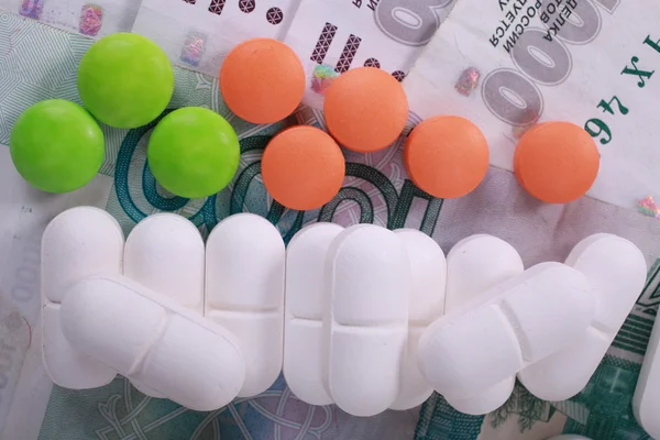 Pills of different colors on money background. — Stock Photo, Image