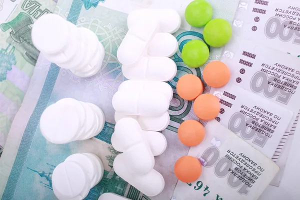 Pastillas de diferentes colores sobre fondo de dinero . — Foto de Stock