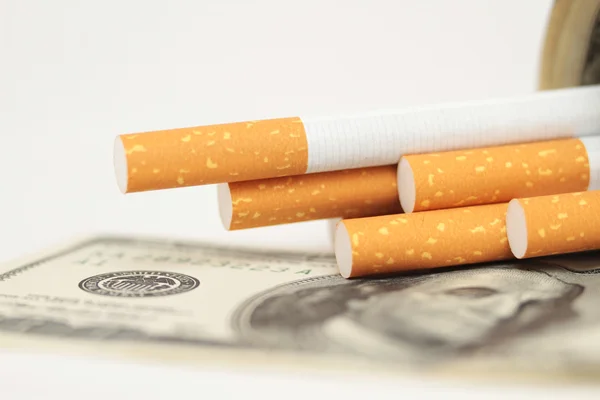 Zigaretten und Geld. Teure Gewohnheit. weißer Hintergrund - horizontales Foto. — Stockfoto