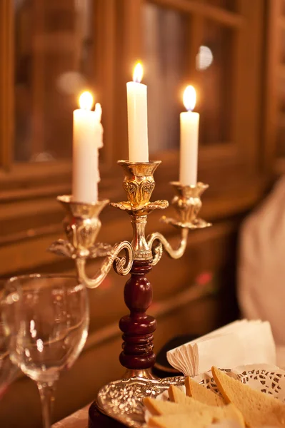 The burning candles in a candlestick on a festive table — Stock Photo, Image