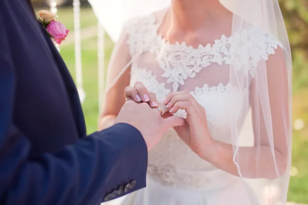 A noiva usa uma aliança de casamento no dedo do noivo — Fotografia de Stock